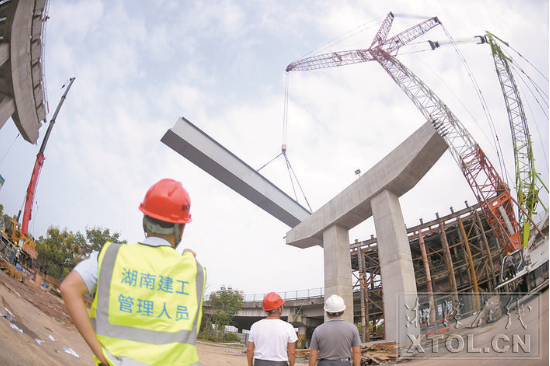 紅易-滬昆跨線橋跨滬昆高速公路主跨架梁施工現(xiàn)場，一節(jié)節(jié)鋼箱梁被吊起安裝。（記者 方陽 攝）